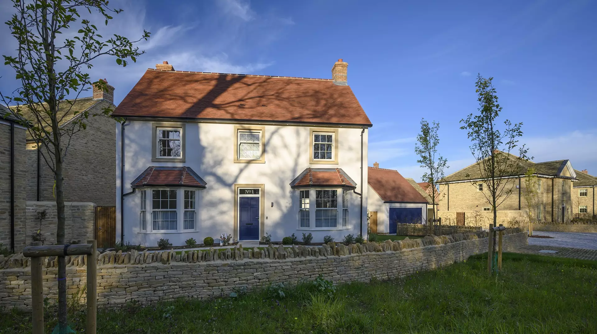 A new house with a red tiled roof behind a stone wall