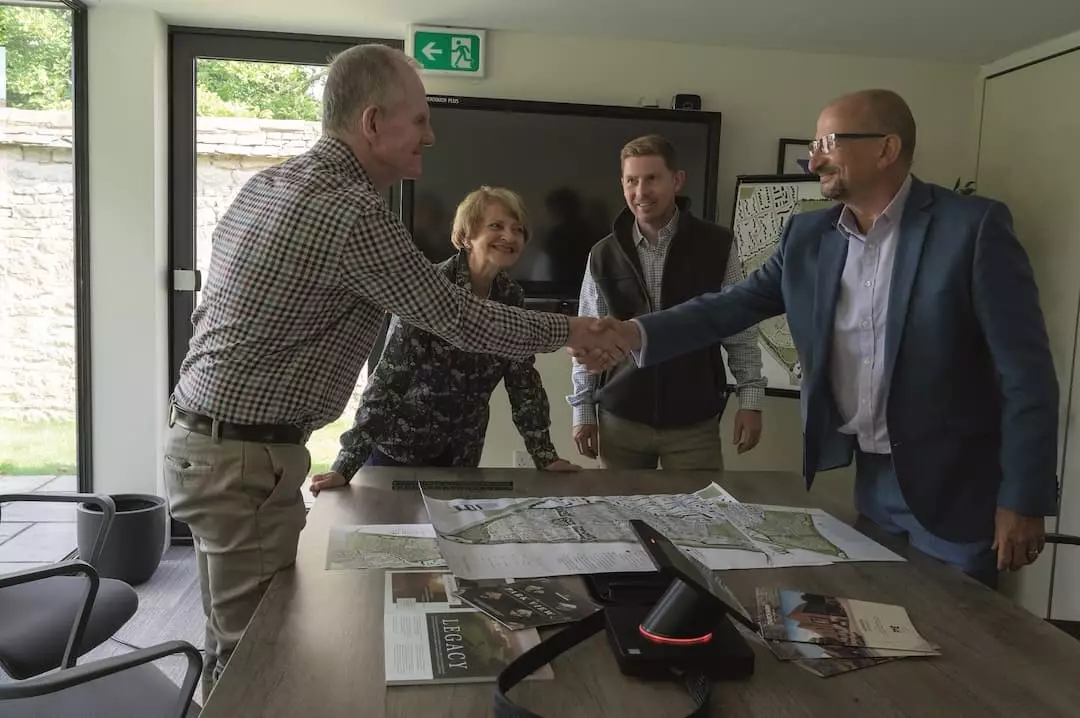 People shaking hands across a table covered with site plans