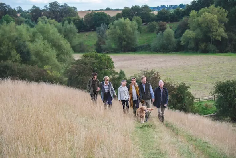 A family and their dog walking down a grassy slope in the countryside